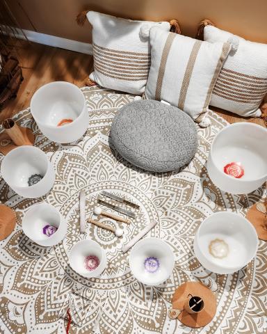 White Frosted Singing bowls set up in a half circle around a grey meditation cushion.