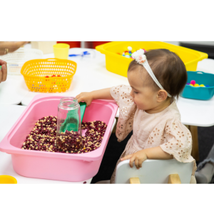 young girl scooping from sensory play bin