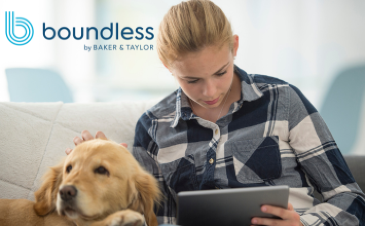 A blonde woman in a black and white flannel shirt reads on a tablet with a golden retriever next to her.